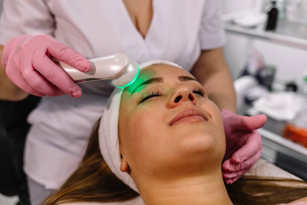 Woman getting laser and ultrasound face treatment in medical center